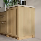 A modern kitchen with light wooden cabinets, featuring light-colored countertops and clean lines.