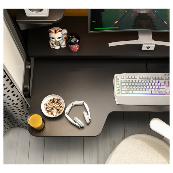 A black FREDDE gaming desk with a keyboard, headphones, snack bowl, and drink. It includes a monitor, decorative items, and a chair.