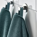 Two green towels hang on chrome hooks in bathroom.