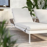 White outdoor lounge chairs with adjustable backrests on a wooden deck.