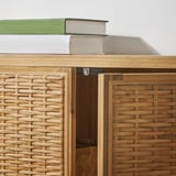 Closed wooden cabinet with woven rattan doors, showing sturdy hinges and natural finish.