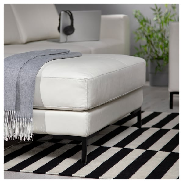 Modern living room with white leather ottoman on black and white striped rug.