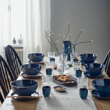 Table set with GLADELIG blue bowls, stoneware, deep & round, perfect for soups & pasta. Centered vase with branches.