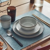 GLADELIG bowl on blue mat with matching dishware, reactive glaze.