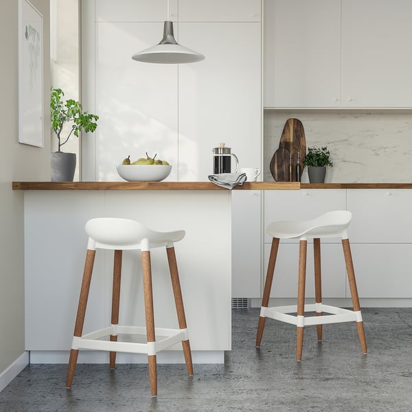 Modern kitchen with white GRÖNSTA stools. Sleek design, wooden legs, comfortable for dining bar height.