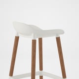 Modern white bar stool with ergonomic seat, four wooden legs, sleek design.