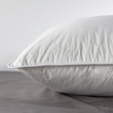 Close-up of a plush, white pillow on a bed, showcasing its soft, inviting texture.