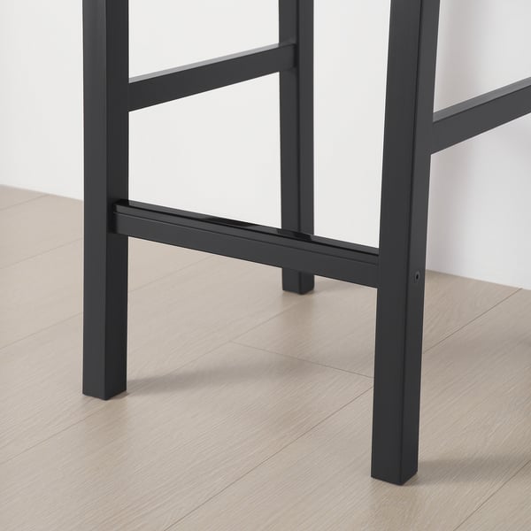 Black metal legs of a modern table on a wooden floor. Sturdy and minimalist design.