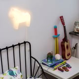 Bedside lamp shaped like a horse head illuminating a childs bedroom with toys and books on a nightstand.