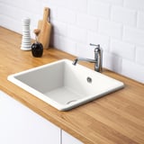 White HAVSEN sink with silver faucet on wooden countertop, including water trap and strainer.