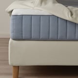 Close-up: divan bed with soft, supportive headboard and wooden legs, showing removable, machine-washable cover.