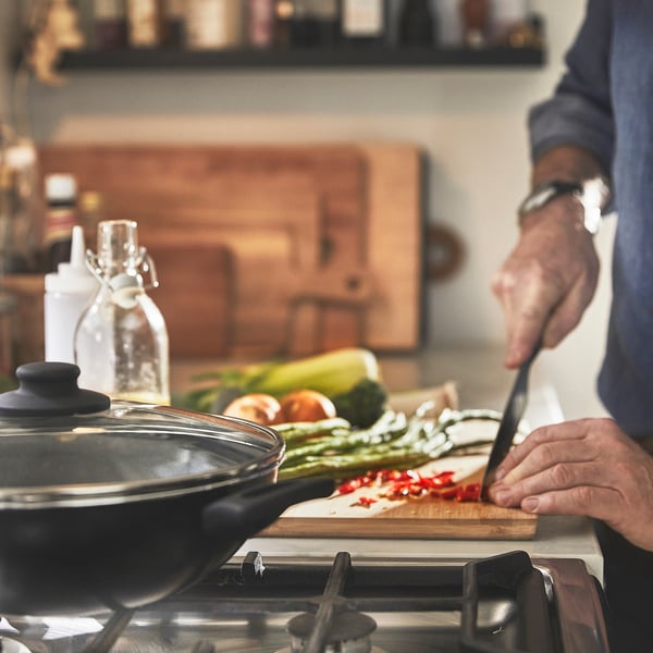Person prepping veggies; wok ready on stove.