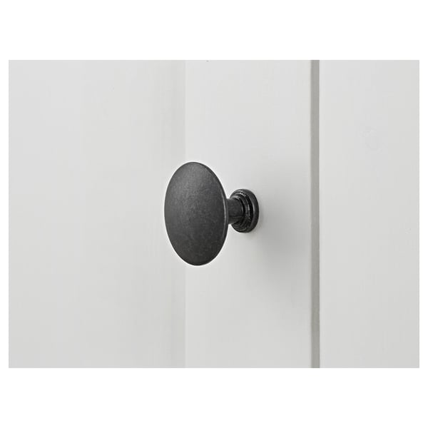 Black round knobs on white wooden surface; minimalist design.
