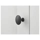 Black round knobs on white wooden surface; minimalist design.