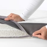 Person opening a zipper on a washable mattress cover.