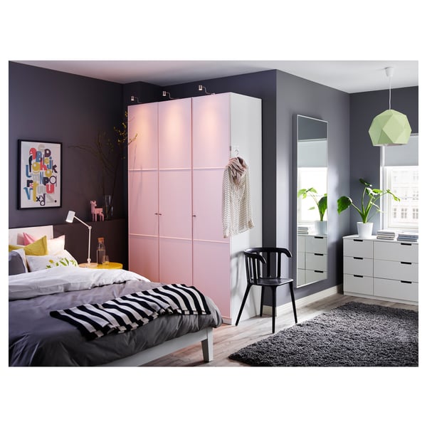 Modern bedroom with light pink closet, black and white bedding, large mirror, black rug, and green lamp shade.