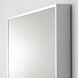 Large, sleek mirror with narrow frame, leaning against wall. Modern, minimalist design. Safety film on glass.