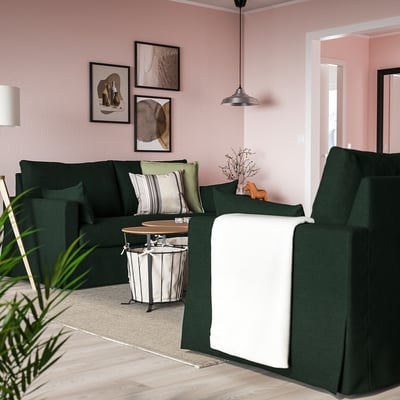 Green HYLTARP sofa in cosy living room with pink walls, artwork, and hanging lamp.