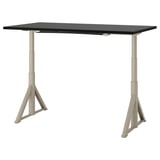 An IDÅSEN desk, rectangular with a black top and beige legs. Its adjustable, sturdy, and has a cable management solution.