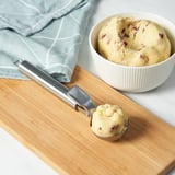 Ice cream scooper with bowl, quick release function, non-stick, ergonomic handle, blue cloth background.