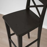 Black wooden bar stool with square seat and backrest, part of the INGOLF series, placed on a light wooden floor.