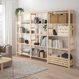 Natural wood IVAR shelving unit, filled with books, baskets, and decorative items. Tall, rectangular, fits well with large couch and rug.
