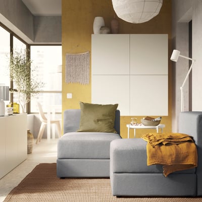 Modern living room with JÄTTEBO sofa, throw blanket, cushion, cabinet, and pendant light.