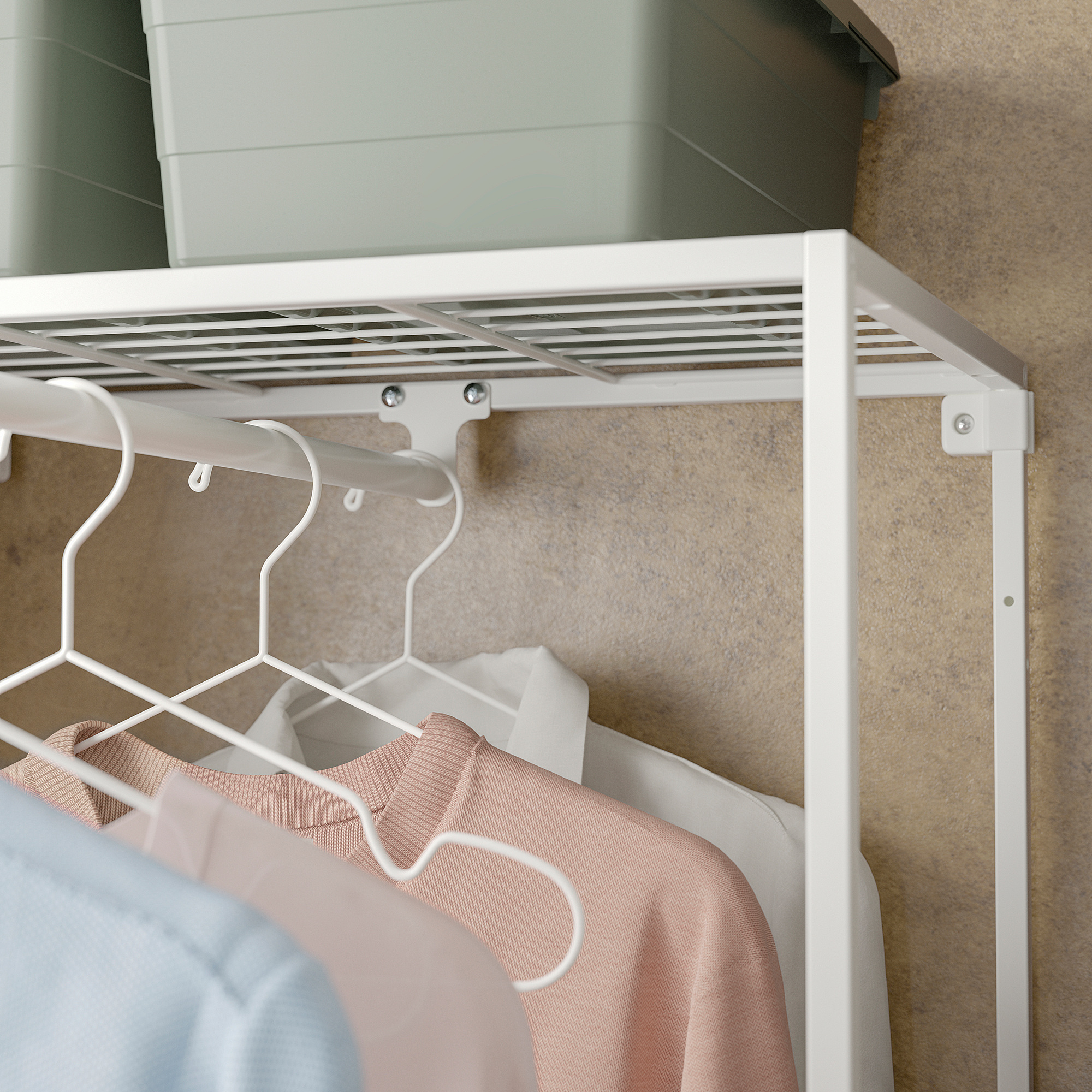 White JOSTEIN clothes rack with hanging shirts, installed in a closet.