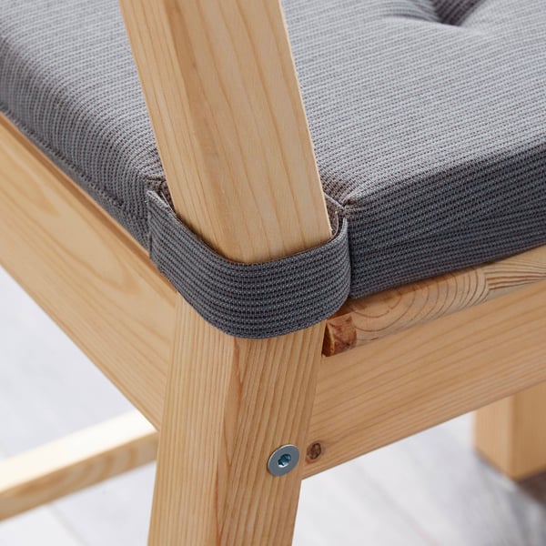 A wooden chair with a grey cushion, secured by elastic straps, ensuring comfort and stability.