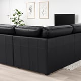 Modern living room with large black KIVIK leather sofa, wide armrests, flat-screen tv, and plant. Sofas size dominates room.