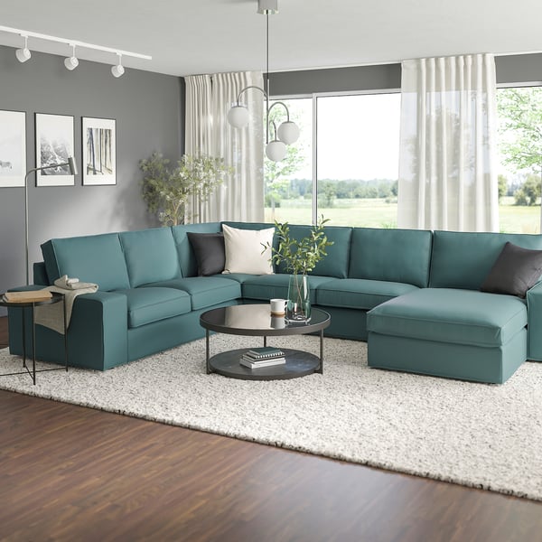 Turquoise KIVIK sectional, black coffee table, white rug, large windows with field view.