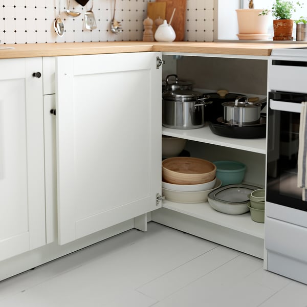 Kitchen cabinet with pots, pans, wooden board, and bowls on oak worktop and laminate shelf.