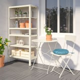 KOLBJÖRN outdoor table & chair set; metal, plastic seat. White shelving unit displays plants & tools beside.