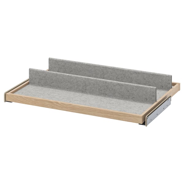 An ikea KOMPLEMENT pull-out tray. It has a wooden frame, grey felt bottom, and dividers. Ideal for organizing small items.