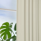 Beige KORGMOTT block-out curtains with woven texture, offering privacy and light control, shown partially drawn with a green leafy plant nearby.