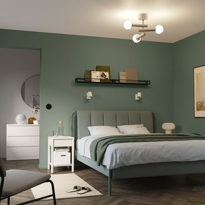 Modern bedroom with green walls, white ceiling lamp, and white furniture.