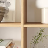 Setup of light wooden shelves holding various home decor items like vases and a plant.