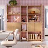 Home office with LÅDMAKARE shelves, books, decor, chair, lamp, pink walls.