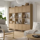 Wooden LÅDMAKARE storage unit with open & closed shelves against wall, displaying decor items & books in a white room.