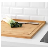 Wooden cutting board with juice groove holds leeks and knife.