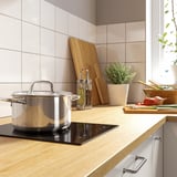 Modern kitchen with stove, wood counter, knives, and plants.