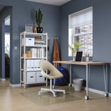 Modern home office with white LAGKAPTEN desk, chair, and bookshelf against dark blue wall.