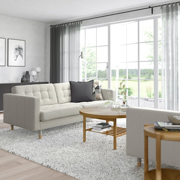 Modern living room with grey LANDSKRONA sofa, large window, wooden tables, and pillows.