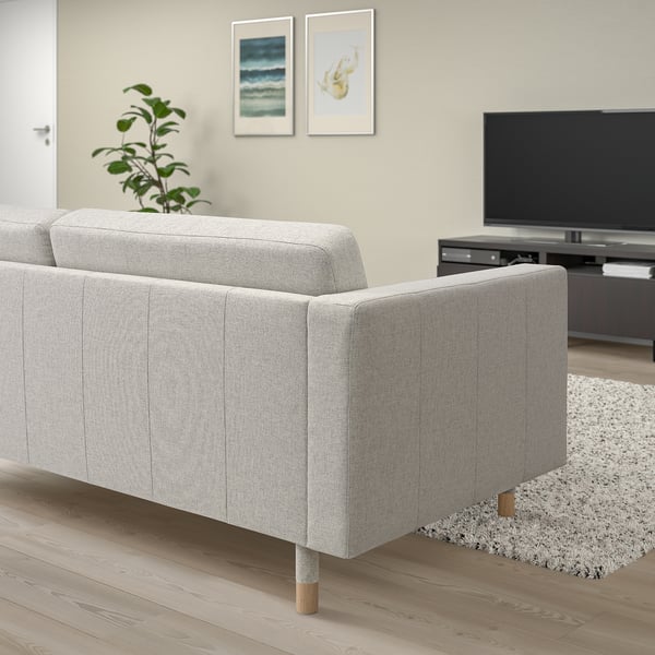 Modern minimalist living room: gray LANDSKRONA sofa, light wood floor, white rug, tv, wall art, plant.