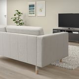 Modern minimalist living room: gray LANDSKRONA sofa, light wood floor, white rug, tv, wall art, plant.