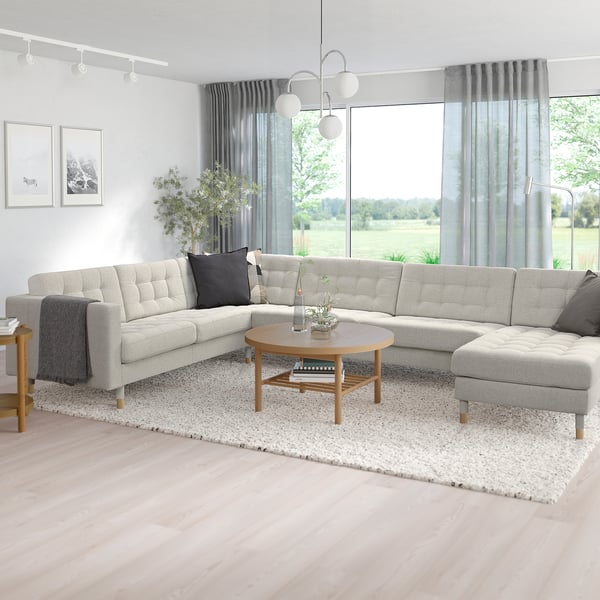 Modern living room with large grey l-shaped LANDSKRONA sofa, wooden coffee table, and big windows.