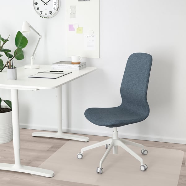 Home office setup: white desk, blue LÅNGFJÄLL chair, white lamp, plant, clock.