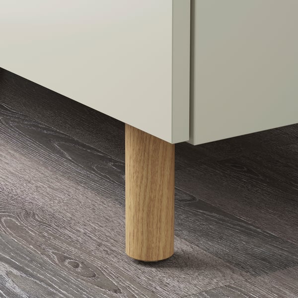 Cylindrical wooden cabinet leg, polished light wood, attached to modern cabinet with smooth edges.