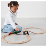 Child playing with LILLABO train set, connecting magnetic wagons on wooden track.