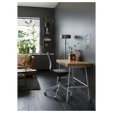 Modern home office with LILLÅSEN bamboo desk, black chair, grey decor, and floor plants.
